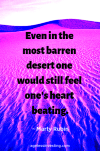 A pink, blue, and purple desert landscape, with the quote "Even in the most barren desert one would still feel one's heart beating." ∼Marty Rubin