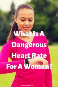 A picture of a young brown-haired woman wearing a pink long-sleeved shirt looking at her fitness watch, with the headline: "What Is A Dangerous Heart Rate For A Woman?"